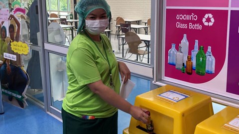 Thailändsk medarbetare slänger avfall på en återvinningsstation